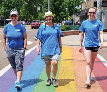 Three employees walking on pride colored walkway