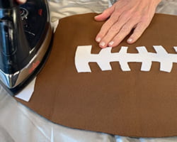 Person ironing a placemat in shape of a football