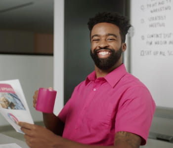 Marcus wearing a magenta shirt drinking out of coffe mug