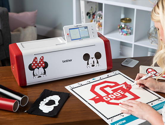 ScanNCut SDX230Di with Mickey and Minnie Mouse designs on table with woman using cutting mat