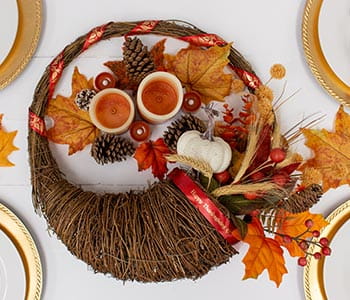 Cornucopia centerpiece with Ptouch Embellish ribbon and orange leaves and pinecones on a table.