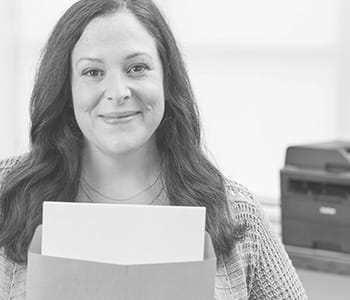 Woman holding envelope with printer in background